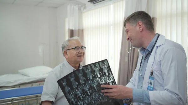 Asian elder adult having a consult with doctor about his disease, doctor explains the x-ray film to Asian senior adult. Health care and wellness in aging society.