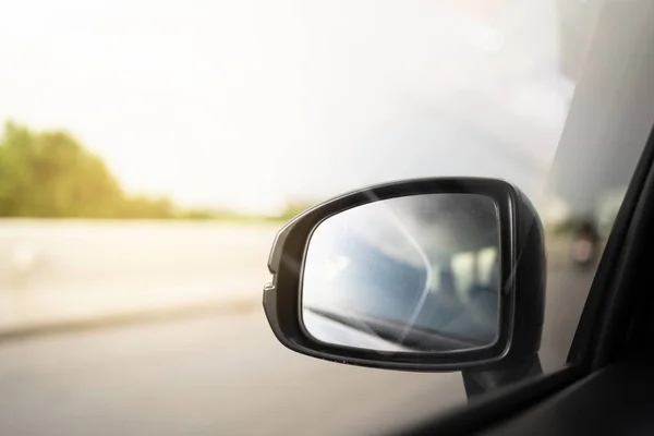 Vehicle side mirror while vehicle moving on the highway with copyspace. Safety driving concept.