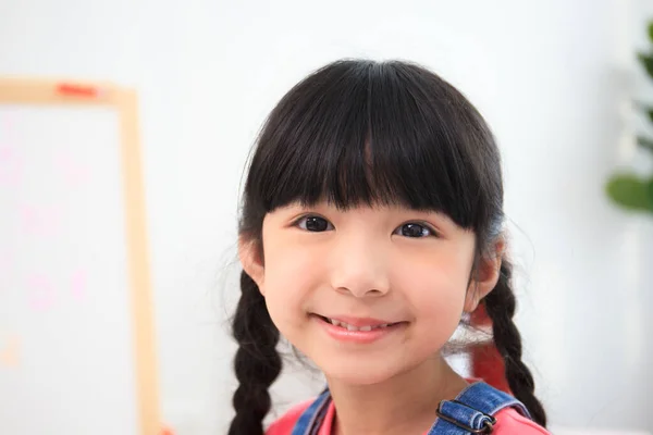 Little happy Asian girl smiling and looking at camera. Innocent little preschool - kindergarten Asian girl portrait in the classroom.