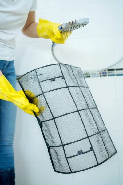 Asian woman cleaning a dirty and dusty air conditioning filter in her house. Housewife removing a dusty air conditioner filter.