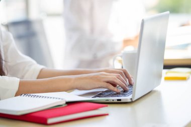 Ofiste çalışan bir kadın kişisel dizüstü bilgisayarını kullanarak bilgisayarın klavyesini kapatıyor. Ofis kadını e-posta ve sosyal medya göndermek için dizüstü bilgisayar kullanıyor.