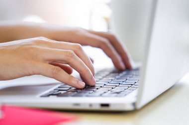 Ofiste çalışan bir kadın kişisel dizüstü bilgisayarını kullanarak bilgisayarın klavyesini kapatıyor. Ofis kadını e-posta ve sosyal medya göndermek için dizüstü bilgisayar kullanıyor.