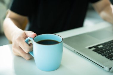 Masada dizüstü bilgisayar ve bir fincan kahve. Evdeki modern işyeri ve modern çalışma tarzı.
