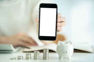 Boş ekran akıllı telefonundaki kırpma yolu ile izole edilmiş. Para biriktirme ve yatırım konsepti. Genç bir kadın para biriktirerek boş bir akıllı telefon ekranı gösteriyor..