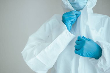 Tanımlanamayan uzman doktor hastanede çalışmadan önce tıbbi bir PPE giysisi giyer. Koronavirüs için kişisel koruma ekipmanı veya PPE giysisi kullanımı - COVID-19 salgını.