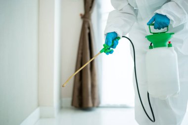 Binanın içindeki bir yüzeyi sterilize eden sağlık personeli koronavirüs ya da COVID-19 salgınına neden olur. Temizlikçi, COVID19 virüsünden arınmak için temiz kimyasal sprey kullanıyor..