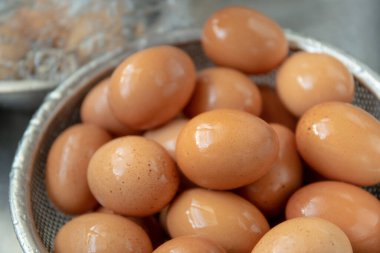 Tanınmayan Asyalı ev hanımı lavaboda çiğ yumurta yıkıyor yakından, kadın mutfakta pişirmeden önce kirli yumurta kabuğunu temizliyor ve hazırlıyor..
