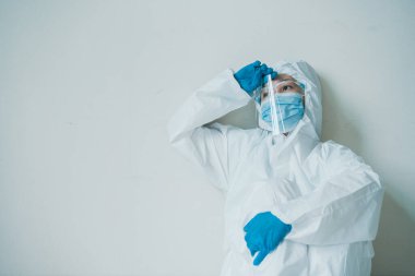 Stresli, endişeli Asyalı ilaç personeli duvardaki sandalyede oturuyor, sağlık çalışanı hastanede çok çalışıyor. Aşırı çalışan sağlık görevlisi - hemşire yorgun hissediyor.