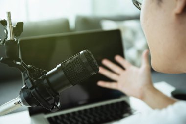 Ev podcast 'i yapan tanınmayan Asyalı genç adam ya da online radyo canlı yayını yapan ve dizüstü bilgisayar ya da defter ekranına bakan. Canlı yayın ve podcast performansı.