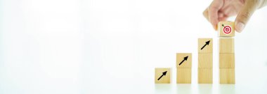 Telif uzayı olan tahta bloklarda iş büyütme konseptinde yaratıcılık. Hedef tahtasını ve ok simgesini listenin başına koyan adam.