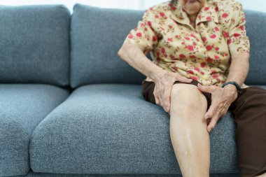 Asian elder woman having a critical health problem at knee and bone joint, woman touching or holding at knee. Elder woman getting hurt and injured at her leg.