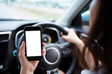 Empty screen smartphone isolated with clipping path. Unrecognizable careless woman using a smartphone while driving a car on highway. Dangerous driving behavior and careless people concept.