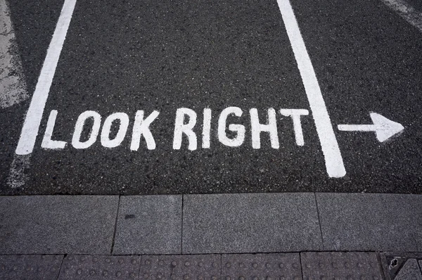 Waarschuwingsbericht "kijk rechts" op voetpad kruising straat — Stockfoto