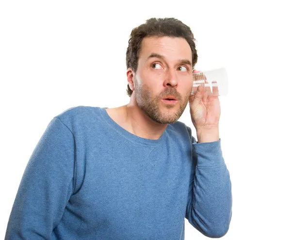 Hombre escuchando a través de un vaso (en la pared ficticia ) — Foto de Stock