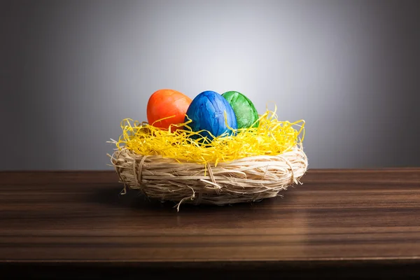 Pasen nest met gekleurde eieren op tabel, grijze achtergrond — Stockfoto