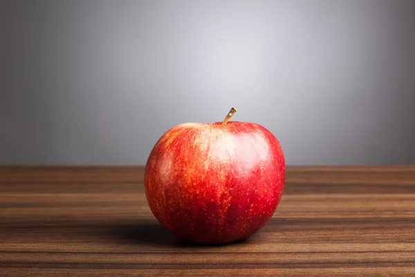 Червоне яблуко на столі, сірий фон — стокове фото