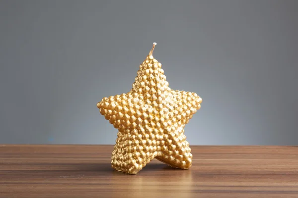 Свеча в форме золотой звезды на столе — стоковое фото