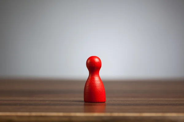 Giocattolo della figura del pedone rosso, tavolo, sfondo grigio . — Foto Stock