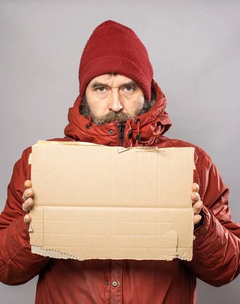 Mature man with cardboard sign in thick winter coat at freezing cold temperatures