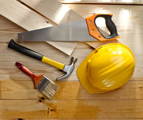 Wood floor with a brush, saw, hammer and helmet — Stock Photo, Image