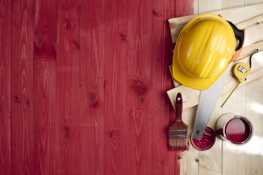 kırmızı ahşap yerde bir fırça, boya, araçlar ve kask