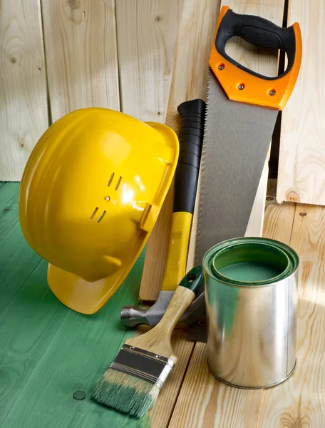Suelo de madera verde con pincel, sierra, martillo y casco — Foto de Stock