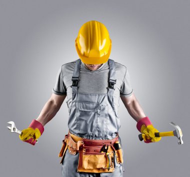 builder in a helmet with a hammer and a wrench clipart