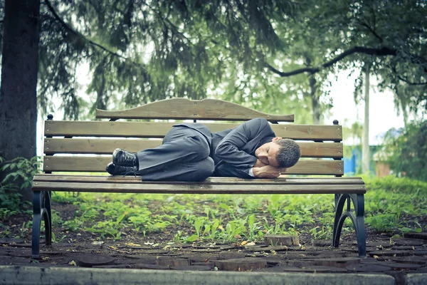 Mann im Anzug schläft auf der Straßenbank Stockbild