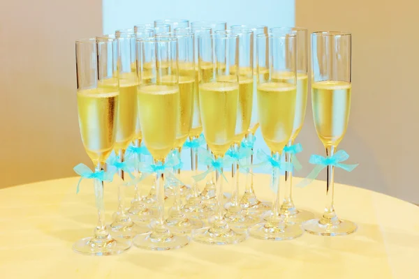 Glasses of champagne with blue wedding ribbons on the table. Sparkling beverage — Stock Photo, Image