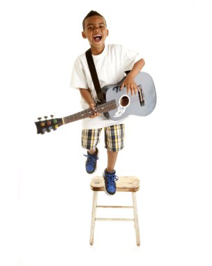 küçük çocuk bir şarkı gitar ile gerçekleştirir.