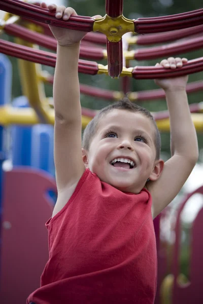 HIspanic little boy swinging from monkey bars — Stock Photo, Image