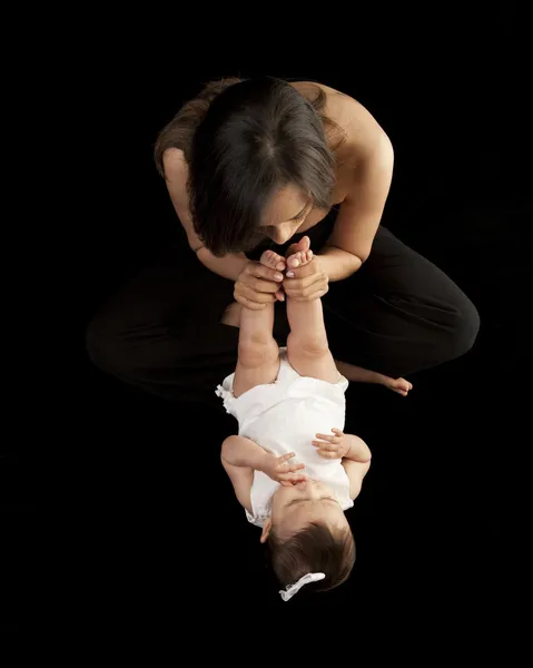 Mother playing with her baby daughter, kissing her tiny feet and toes — Stock Photo, Image