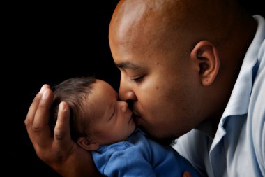 African american father cuddling and kissing his newborn son