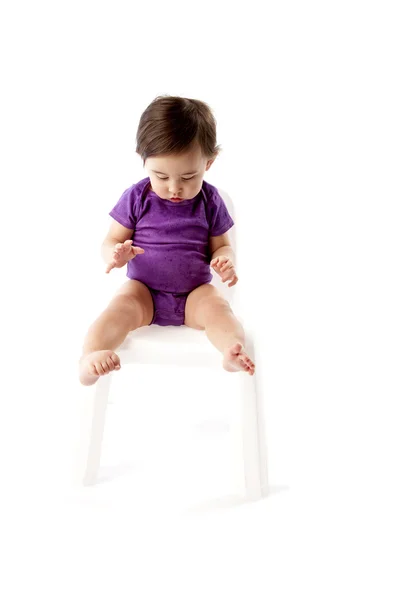 Niña feliz usando camiseta sentada en una silla y mirando hacia abajo —  Fotos de Stock