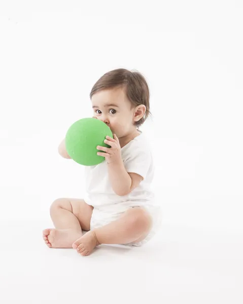 Baby flicka sitter på golvet och leker med en boll — Stockfoto