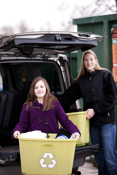 Mother and daughter recycling trash at recycling center