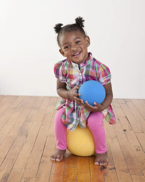 Κορίτσι μικρό παιδί που κάθεται σε μια κίτρινη μπάλα — Φωτογραφία Αρχείου