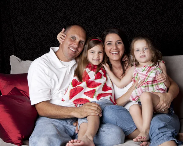 Радісна сім'я з двома дітьми, які грають на дивані — стокове фото