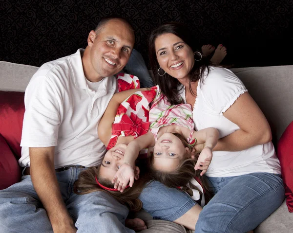 Família feliz com dois filhotes brincando no sofá — Fotografia de Stock