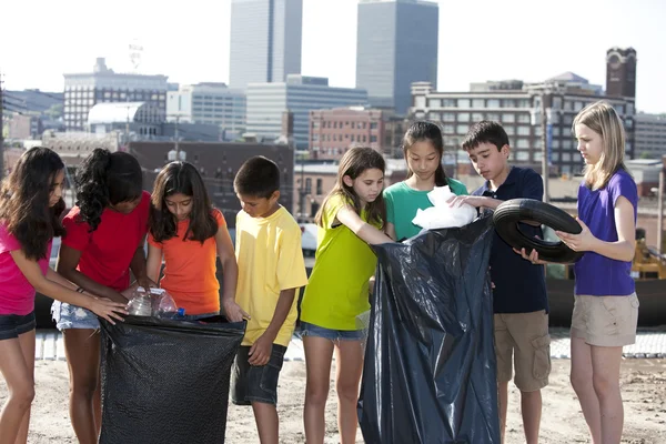 Gruppo di bambini di diverse etnie che raccolgono rifiuti in un'area urbana — Foto Stock