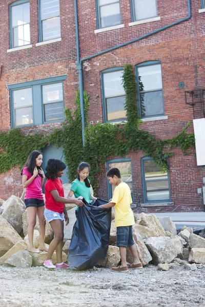 Gruppe von Kindern verschiedener ethnischer Zugehörigkeiten, die Müll in einem städtischen Gebiet aufsammeln — Stockfoto