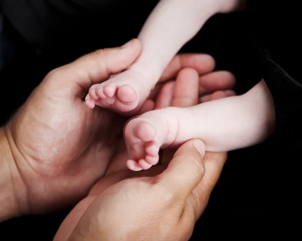 Les mains du père tenant de minuscules pieds de nouveau-né — Photo