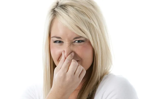 Caucasian young adult woman holding her nose as if she smells something bad — Stock Photo, Image