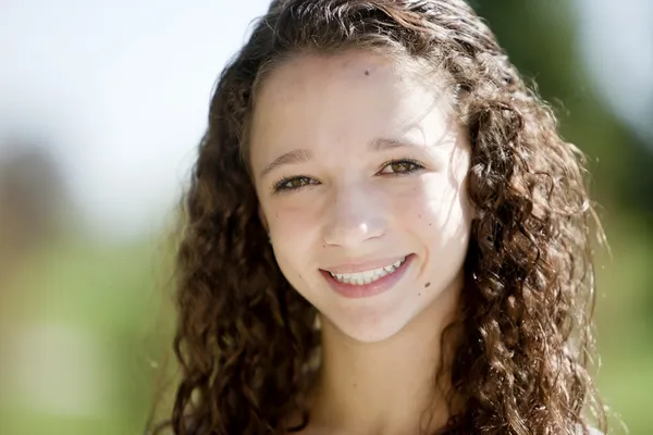 Χαμογελώντας χαριτωμένο εφηβικό κορίτσι με σγουρά μαλλιά στο πάρκο — Φωτογραφία Αρχείου