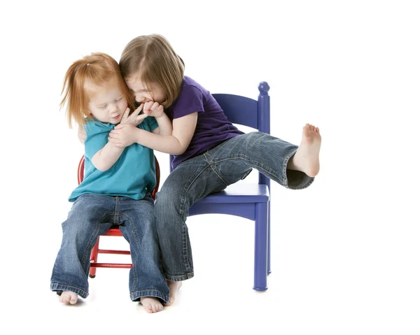 Two sisters sitting together and playfully wrestling — Stock Photo, Image