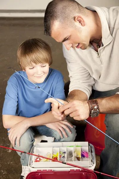 Ung man att hjälpa unga pojke med fiskeutrustning Stockfoto