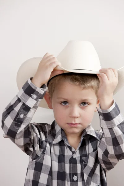 Serious little boy with cowboy hat and a plaid shirt Stock Photo