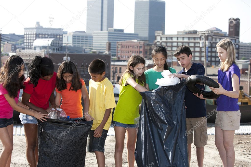 Group of children of different ethnicities picking up trash in an urban area