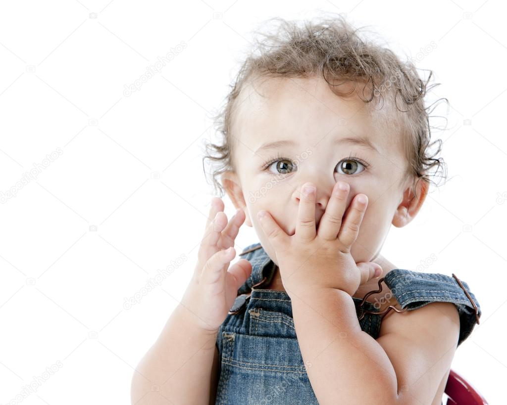 Toddler boy covers mouth with his hands