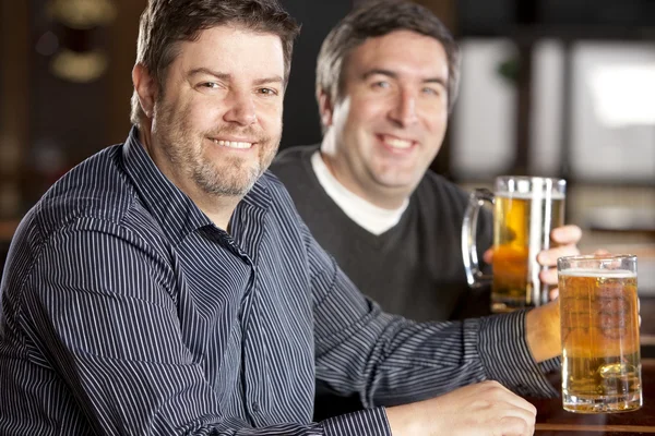 Homens adultos caucasianos sentados em um bar com canecas de cerveja . — Fotografia de Stock